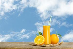copo de suco de laranja fresco na mesa de madeira, suco de laranja de frutas frescas em vidro com grupo no fundo do céu azul com espaço de cópia para o seu texto.