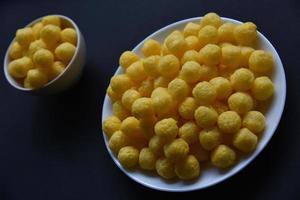 batatas fritas salgadas e apimentadas de milho em um prato branco. delicioso café da manhã de salgadinhos de milho em um fundo preto. foto