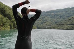 atleta de triatlo se preparando para treinamento de natação no lago foto