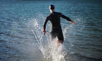 atleta de triatlo iniciando treinamento de natação no lago foto