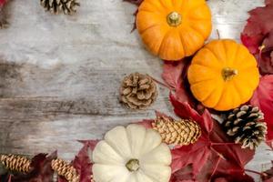 decoração festiva de outono de abóboras, pinheiros e folhas em um fundo de madeira. conceito de dia de ação de graças ou halloween. composição de outono plana leiga com espaço de cópia. foto