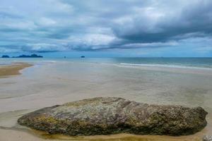 rochas à beira-mar na bela praia de manhã com nuvem de chuva. foto