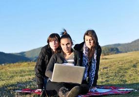 grupo de adolescentes trabalhando no laptop ao ar livre foto