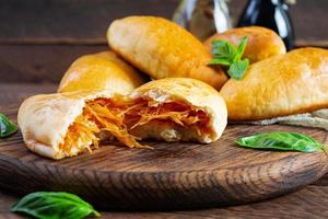 tortas de repolho russo tradicional em fundo de madeira. pirozhki caseiro assado com repolho foto