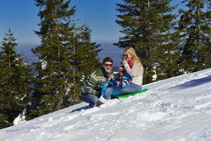 família se divertindo na neve fresca no inverno foto