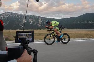 cinegrafista tomando uma foto de ação do atleta de bicicleta de triatlo