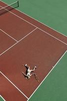 jovem jogar tênis ao ar livre foto