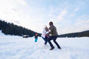 família feliz jogando juntos na neve no inverno foto