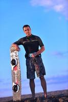 retrato de um jovem kitsurf na praia ao pôr do sol foto