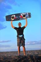 retrato de um jovem kitsurf na praia ao pôr do sol foto