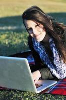 jovem adolescente trabalha no laptop ao ar livre foto