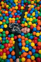 jovem mãe brincando com crianças na piscina com bolas coloridas foto