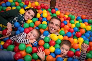 pais e filhos brincando na piscina com bolas coloridas foto