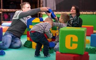 jovens pais e filhos se divertindo na sala de jogos para crianças foto