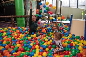 jovem mãe com seus filhos em uma sala de jogos infantil foto