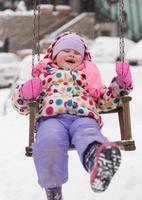 menina no balanço de dia de inverno nevado no parque foto