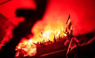 hooligans de futebol com máscara segurando tochas no fogo foto