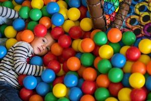 menino se divertindo na piscina com bolas coloridas foto