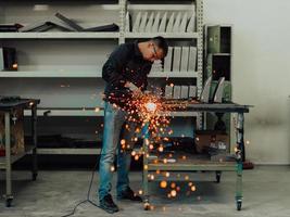 interior da fábrica de engenharia da indústria pesada com trabalhador industrial usando rebarbadora e cortando um tubo de metal. empreiteiro em uniformes de segurança e fabricação de capacetes de estruturas metálicas. foto