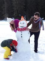 família feliz fazendo boneco de neve foto