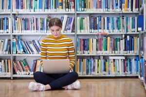 o aluno usa um notebook e uma biblioteca escolar foto