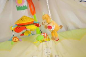 cama de bebê com brinquedos coloridos interior foto