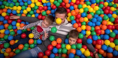 pai e filhos brincando na piscina com bolas coloridas foto