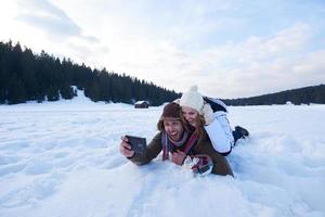 casal romântico se diverte na neve fresca e tirando selfie foto