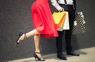 mulher irreconhecível de vestido vermelho e homem segurando sacolas de compras. foto