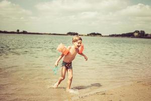 menino feliz se divertindo em dia de verão na praia. foto
