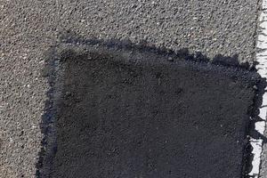 a parte reparada de uma estrada de asfalto com remendos foto