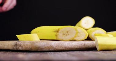 corte uma banana amarela madura em vários pedaços com um cutelo foto