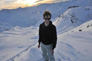 jovem feliz se divertir no inverno no pico da montanha foto