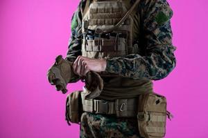 closeup de mãos de soldado colocando luvas de batalha protetoras fundo rosa foto