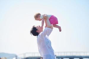 mãe e bebê na praia se divertem foto