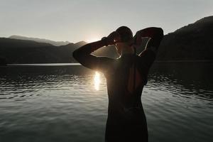 atleta de triatlo iniciando treinamento de natação no lago foto