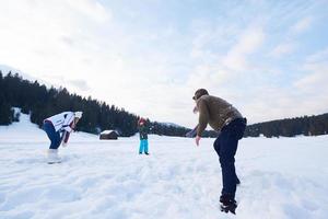 família feliz jogando juntos na neve no inverno foto