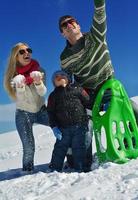 família se divertindo na neve fresca no inverno foto