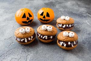 biscoitos com pasta de chocolate em forma de monstros e tangerinas de abóbora para o halloween foto