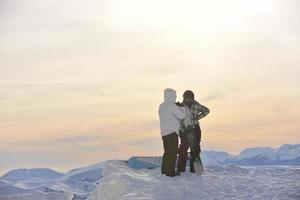 casal de snowboarder no topo da montanha foto