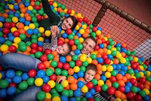 pais e filhos brincando na piscina com bolas coloridas foto