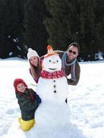 família feliz fazendo boneco de neve foto