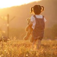 menina triste se sentindo sozinha no conceito de parque. menina solitária linda criança ficar sozinha no parque. ao pôr do sol com flare foto