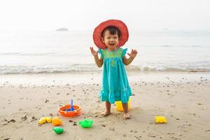 criança feliz, adorável menina loira brincando na praia com brinquedos foto