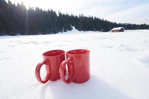 dois golpes vermelhos de bebida de chá quente na neve no inverno foto