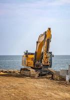 escavadeira de esteira após obras no canteiro de obras na praia do mar foto