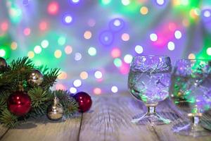 duas taças de champanhe de natal com árvore de natal decorada de bolas vermelhas e prateadas contra fundo bokeh claro foto