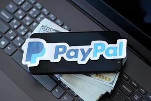 ternopil, ucrânia - 6 de setembro de 2022, o logotipo de papel payoneer está no laptop preto com notas de dólar dos eua. payoneer é uma empresa americana de serviços financeiros que oferece transferência de dinheiro online foto