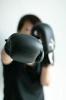 uma mulher em luvas de boxe pretas esticando o punho direito para o alvo da frente. foto