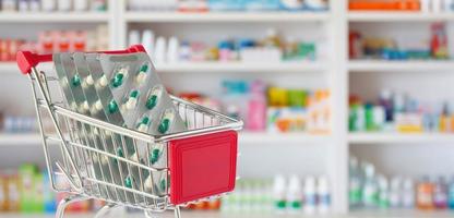 cápsula de comprimidos médicos no carrinho de compras com prateleiras de farmácia de farmácia fundo desfocado foto